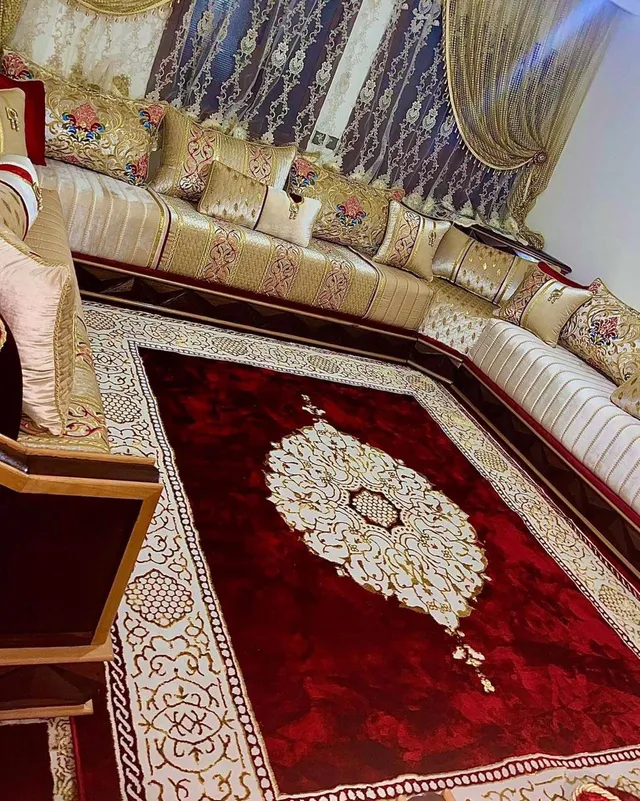 صالون مغربي كريمي وذهبي بوسائد مطرزة وزربية عنابية