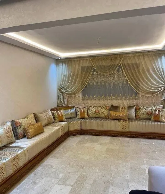 صالون مغربي بيج وذهبي على شكل U مع ستائر ذهبية