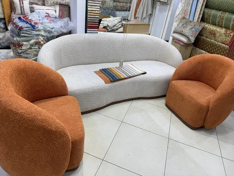 كنبة منحنية بيضاء مع كرسيين برتقاليين